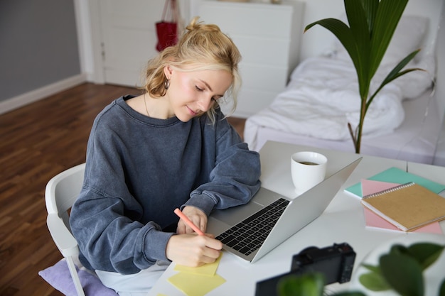 Portrait of smiling young woman female student doing distance learning course using laptop studying