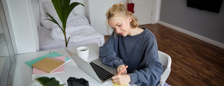 Free Photo portrait of smiling young woman female student doing distance learning course using laptop studying