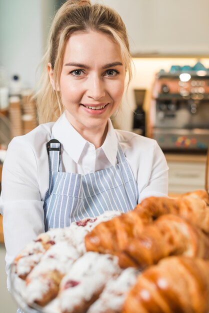 Portrait of a smiling young woman holding fresh baked croissants