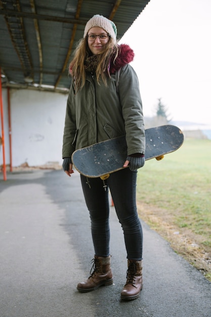 スケートボードを手にしている笑顔の若い女性の肖像