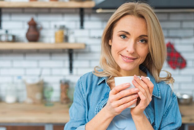 白いコーヒーのカップを手で押し笑顔の若い女性の肖像画