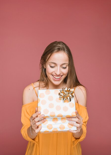 Портрет улыбающейся молодой женщины, глядя на открытую подарочную коробку