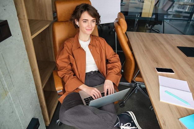 Foto gratuita il ritratto del manager sorridente della giovane donna lavora in ufficio utilizza il laptop funziona dallo spazio di coworking