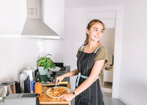 Portrait of smiling young woman preparing pasta in the kitchen