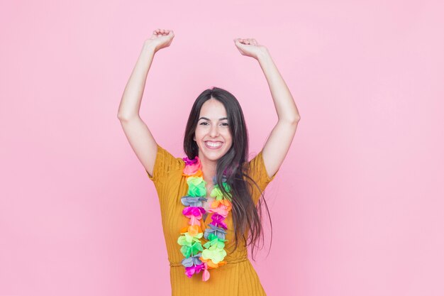 Portrait of a smiling young woman raising her arms on pink background