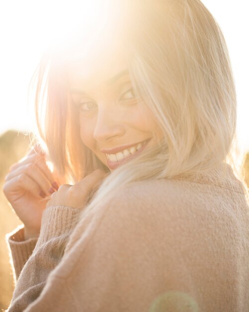 Ritratto di giovane donna sorridente al sole, guardando la fotocamera