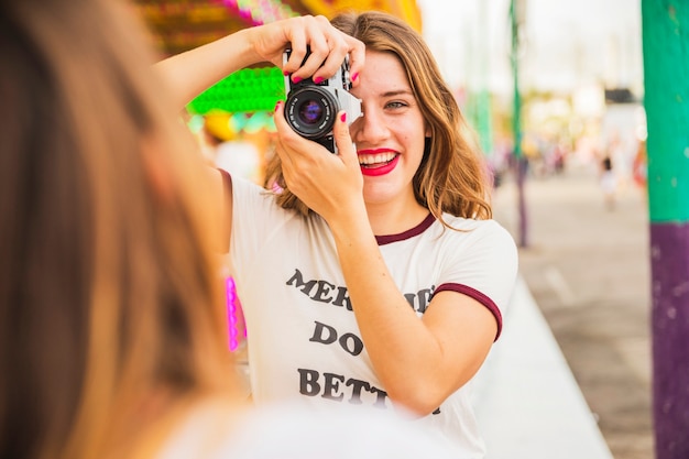 彼女の友人の写真を撮っている笑顔の若い女性の肖像