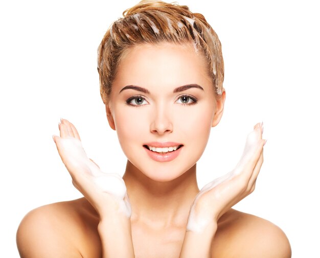 Portrait of a smiling young woman washing her hair on a white