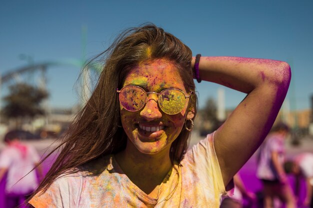 선글라스를 쓰고 웃는 젊은 여자의 초상화는 holi 색상으로 덮여