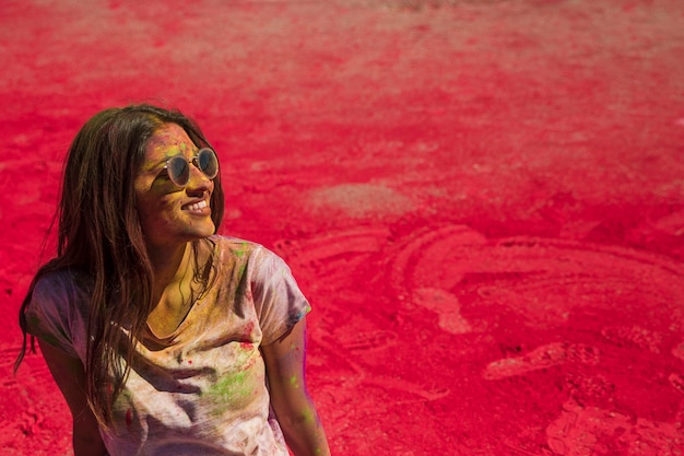 Holi 색상으로 엉망 선글라스를 쓰고 웃는 젊은 여자의 초상화
