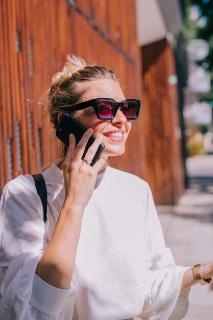 핸드폰에 말하는 선글라스를 쓰고 웃는 젊은 여자의 초상화