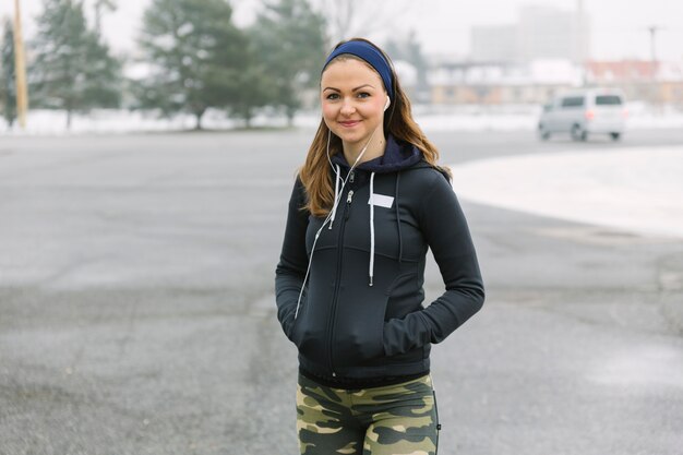 Portrait of smiling young woman with hands in pocket standing on street