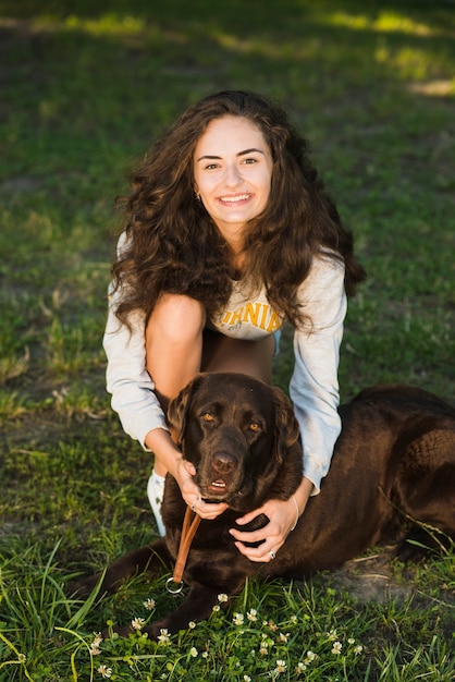 Портрет улыбающейся молодой женщины с ее собакой в ​​парке