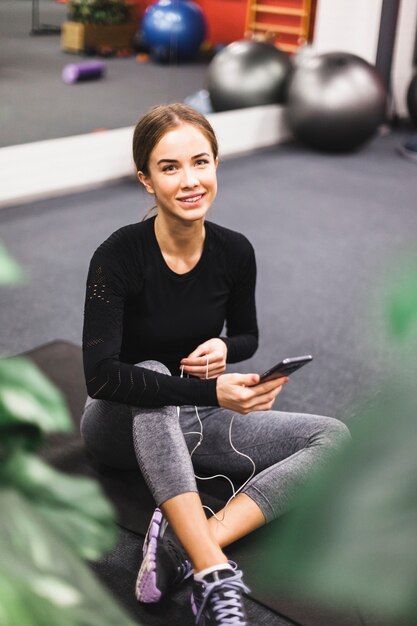 ジムで携帯電話と笑顔の若い女性の肖像画