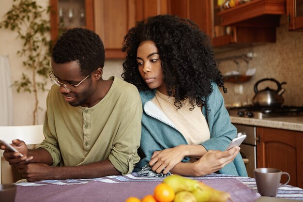 Portrait of sneaky and jealous young African wife spying on her husband