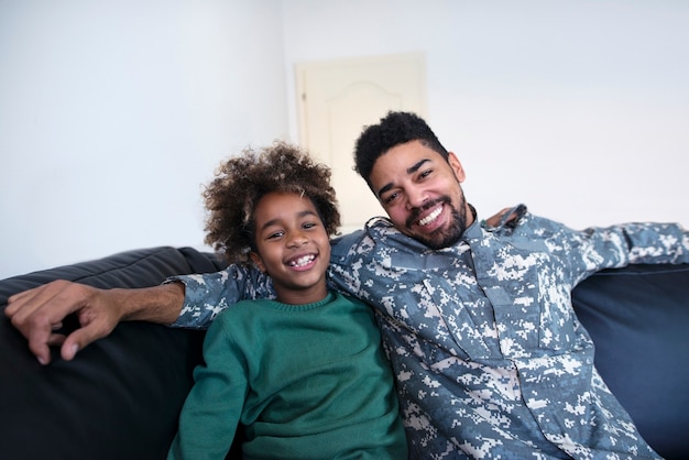 Portrait of soldier in military uniform with his daughter at home