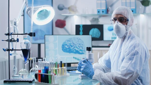 Портрет врача-специалиста с оборудованием ppe, анализирующего образец ДНК, работающего на экспертизе диагностики заболеваний во время микробиологического эксперимента в лаборатории медицинской больницы. Концепция медицины