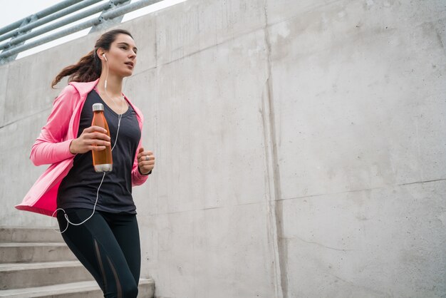 Портрет спортивной женщины, бегущей по лестнице на открытом воздухе. Концепции фитнеса, спорта и здорового образа жизни.