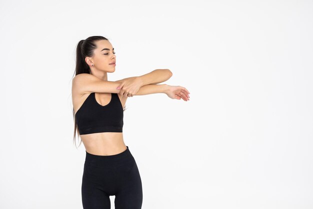 Portrait of a sports woman stretching hands while isolated on a white background