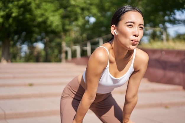 Ritratto di sportiva che ansimava facendo una pausa durante l'allenamento di jogging sudorazione durante la corsa all'aperto