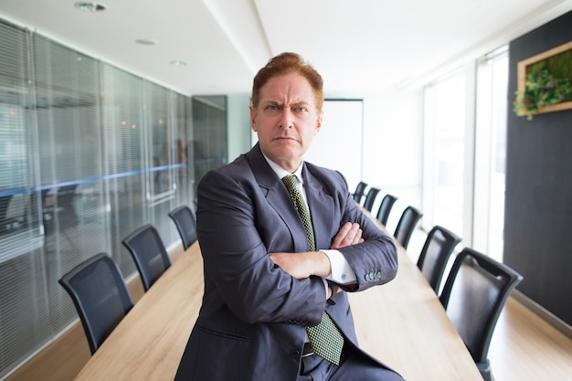 Free photo portrait of stern senior businessman in boardroom