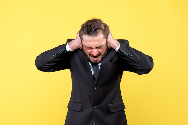 Portrait of stressed young man clsosing his ears