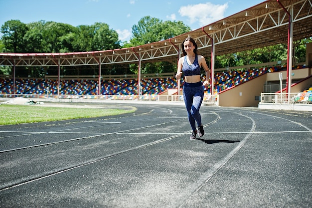 Foto gratuita ritratto di una ragazza in forma forte in abbigliamento sportivo che corre nello stadio