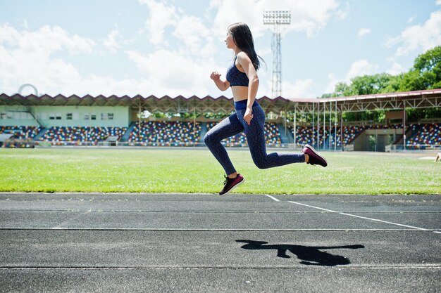 Portrait of a strong fit girl in sportswear running in the stadium