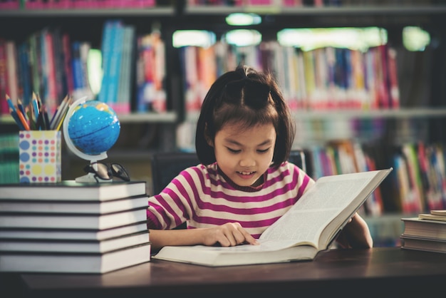 Portrait of a student child girl studying at library