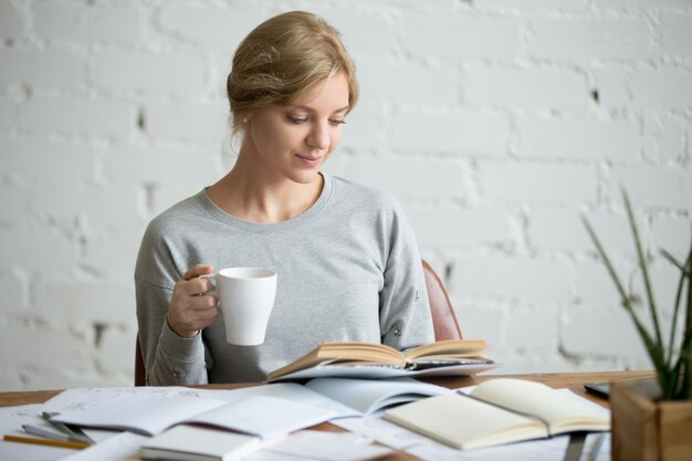 Portrait of student girl at desk with mug in hand