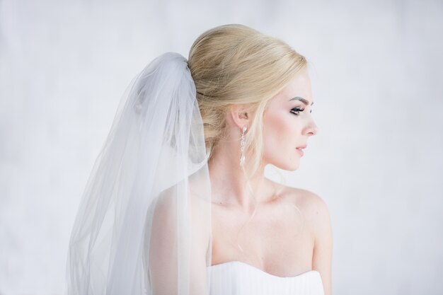 Portrait of stunning blonde bride in dress with naked shoulders