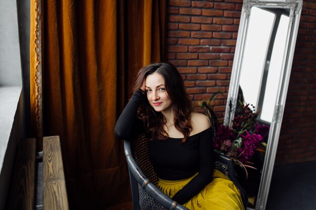 Portrait of a stunning fashionable woman sitting in a chair