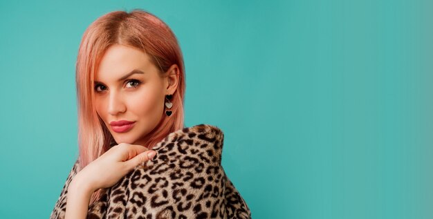 Portrait of stunning woman with pink hair in stylish winter fluffy coat with leopard print