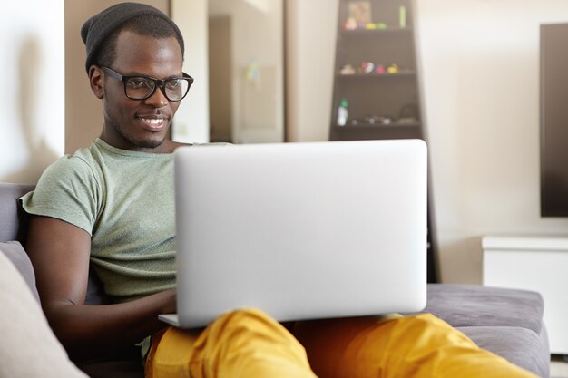 Portrait of stylish African-American man with laptop at home