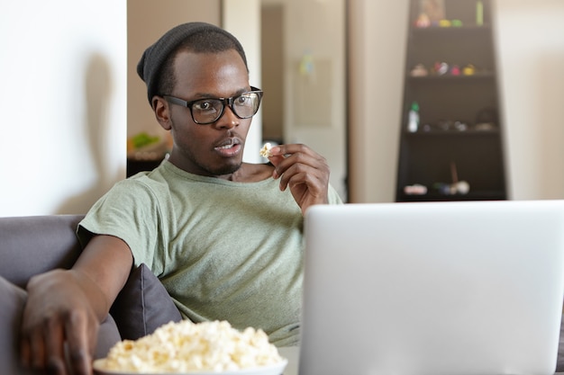 Portrait of stylish African-American man with laptop at home