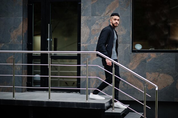 Portrait of stylish arab beard man wear grey turtleneck and black jaket Arabian model guy walking down stairs