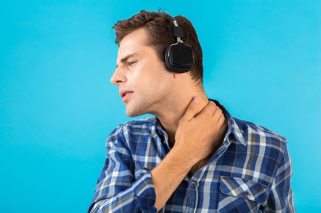 Portrait of stylish attractive handsome young man listening to music on wireless headphones