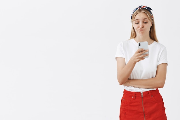 Portrait of stylish attractive young blond girl posing against the white wall