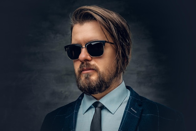 Portrait of stylish bearded hipster male dressed in a jacket, bow tie and sunglasses.