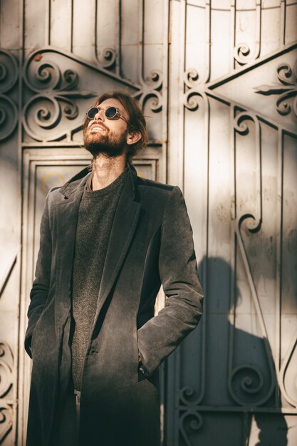 Портрет стильного бородатого мужчины в темных очках и пальто