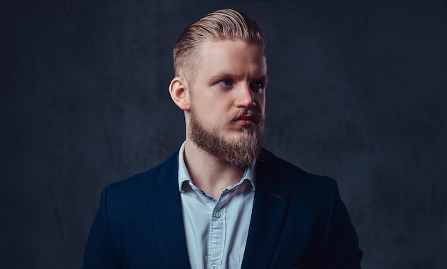 Free photo portrait of stylish blond bearded male dressed in a suit over grey background.