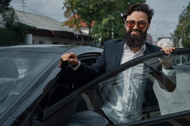 Portrait stylish, handsome man near car outdoors