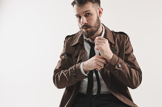 Portrait of stylish handsome young man sitting at studio against white. Man wearing jacket