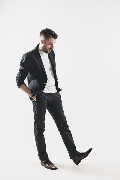 Portrait of stylish handsome young man standing at studio against white. Man wearing jacket