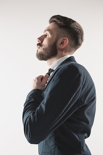 Portrait of stylish handsome young man standing at studio against white. Man wearing jacket