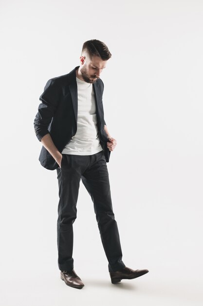 Portrait of stylish handsome young man standing at studio against white. Man wearing jacket