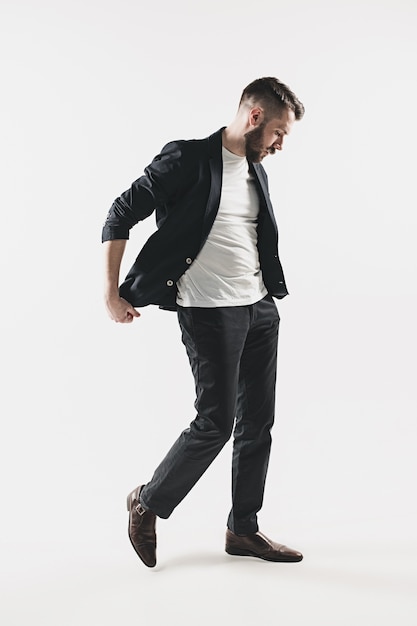 Portrait of stylish handsome young man standing at studio against white.