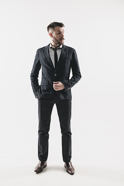 Portrait of stylish handsome young man standing at studio against white.