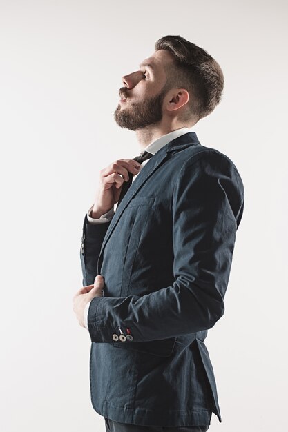 Portrait of stylish handsome young man standing at studio against white.