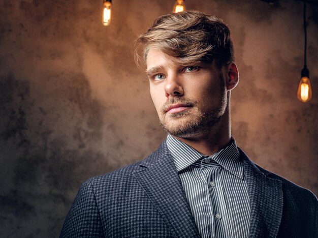 Portrait of stylish maledressed in a suit over grey background.